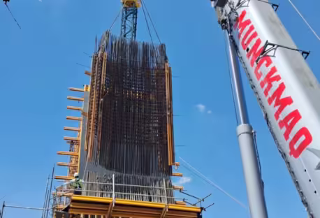 Içamento de carga pesada com guindaste móvel elevando estrutura metálica em canteiro de obras